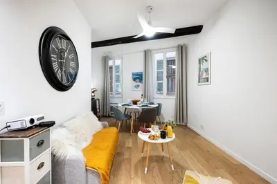 a living room with a couch and a clock on the wall at Le Castelosa - Au coeur du Vieux-Nice in Nice