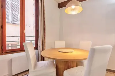 a dining room with a wooden table and white chairs at Proche du Cours Saleya et de la plage, dans le vieux Nice, spacieux et climatisé in Nice