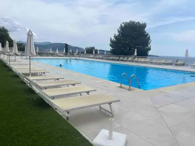 a row of benches next to a large swimming pool at Beautiful Apartment Pool & Garage See View in Nice