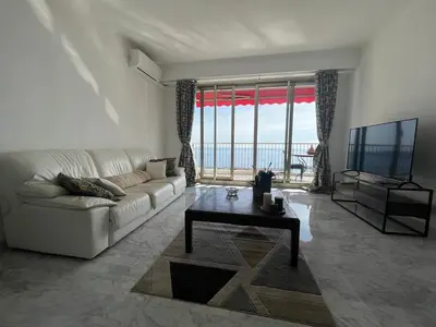 a living room with a white couch and a television at Beautiful Apartment Pool & Garage See View in Nice