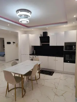 a kitchen with white cabinets and a table and chairs at Cozy appartment downtown Nizza 2 Bedroom 1 min Beach 1 min tramway 10min airport air conditionner in Nice