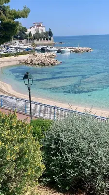 a street light next to a beach with the ocean at La Petite Ancre in Beaulieu-sur-Mer