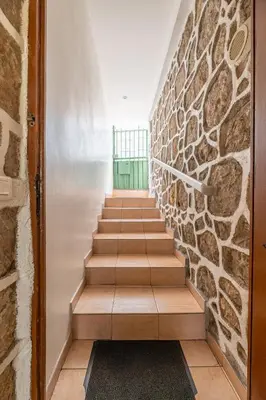 a staircase with a stone wall and a green door at Maison de ville familiale, 5 chambres, terrasse, à 20 minutes du centre ville in Nice
