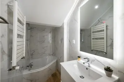 a white bathroom with a tub and a sink and a bath tubermott at Maison de ville familiale, 5 chambres, terrasse, à 20 minutes du centre ville in Nice