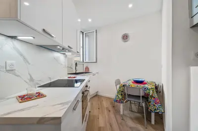 a kitchen with white countertops and a table and chairs at Nice Renting - HONORE - Elegant apartment near Promenade des Anglais in Nice