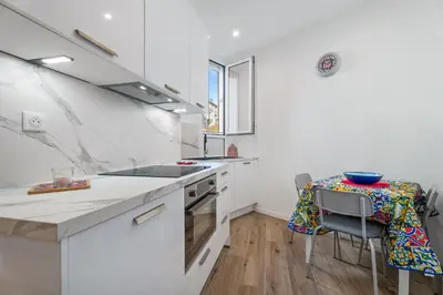 a kitchen with a sink and a table with chairs at Nice Renting - HONORE - Elegant apartment near Promenade des Anglais in Nice