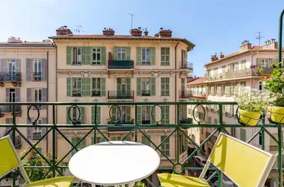 a white table and chairs on a balcony with buildings at French Riviera Escapade - Steps from the Beach in Nice