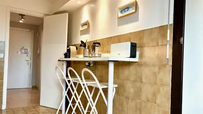 a kitchen with a counter with stools and a microwave at ApartHotel Riviera - Terrasse Felix Faure 2 - Massena in Nice