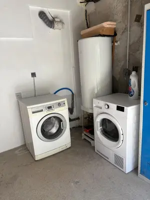a laundry room with a washing machine and a refrigerator at Gîte Le Tilleul in Aspremont