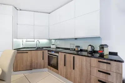 a kitchen with white cabinets and black counter tops at Appartement de la Colline - Welkeys in Nice