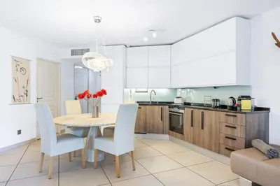 a kitchen with a wooden table and white cabinets at Appartement de la Colline - Welkeys in Nice