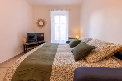 a large bed with pillows and a television in a room at Joli cocon à 3 min à pied de la mer in Nice