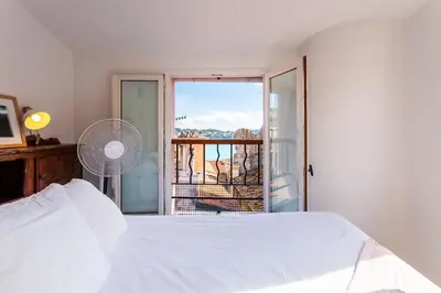 a bedroom with a white bed and a window at PERCHOIR AP4443 By Riviera Holiday Homes in Villefranche-sur-Mer