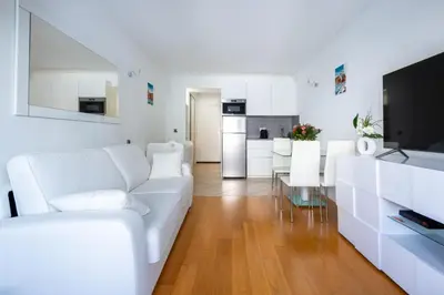 a white living room with a white couch and a kitchen at Azur Central Flat in Nice