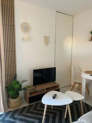 a living room with a television and two white tables at Studio Boho Chic - Proche de la mer in Nice
