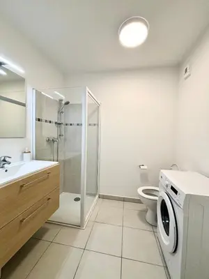 a bathroom with a shower toilet and a washing machine at Nid douillet rénové et tramway à 1 min in Nice