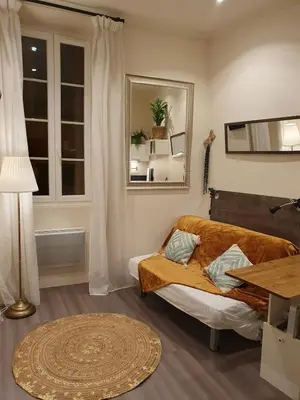 a bedroom with a bed and a table and a window at Studio au cœur du vieux Nice in Nice