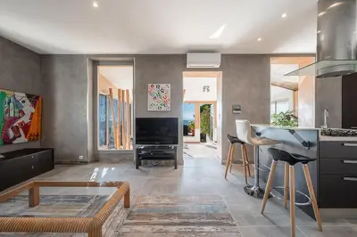 a kitchen with a living room with a table and a stove at Bas de villa plus piscine Vue époustouflante in Villefranche-sur-Mer