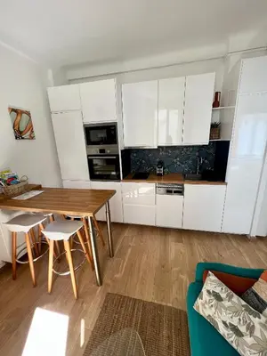a kitchen with white cabinets and a wooden table at T2 centre ville de Nice face de la gare routière Nice ville in Nice