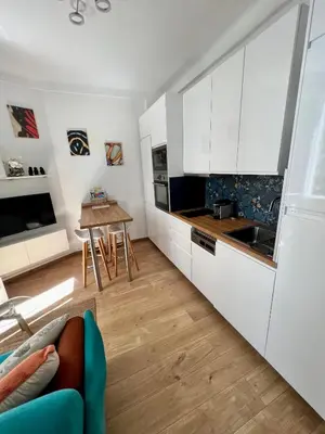 a kitchen with white cabinets and a wooden table at T2 centre ville de Nice face de la gare routière Nice ville in Nice