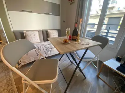 a dining room table with chairs and a bottle of wine at Cosy Studio Promenade in Nice