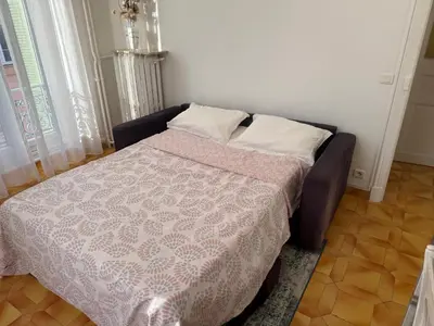 a bedroom with a bed with a pink comforter at Appartement 3 pièces 5 min plage in Beaulieu-sur-Mer