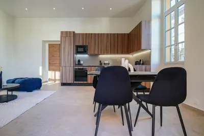 a kitchen with black chairs and a dining table at Massena Infinity in Nice