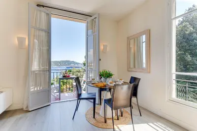 a dining room with a table and chairs and a balcony at BELLE DARSE AP4454 By Riviera Holiday Homes in Villefranche-sur-Mer