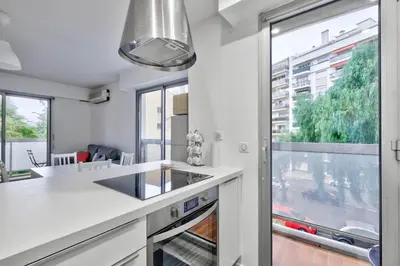 a kitchen with white counters and a large window at Flat with balcony 15min from Promenade des Anglais in Nice
