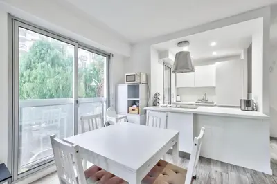 a white kitchen with a white table and a window at Flat with balcony 15min from Promenade des Anglais in Nice