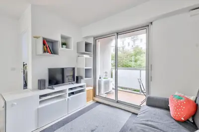 a living room with a couch and a tv and a window at Flat with balcony 15min from Promenade des Anglais in Nice
