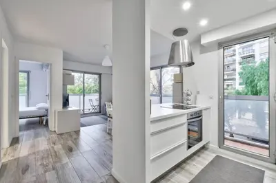 a kitchen with white cabinets and a large window at Flat with balcony 15min from Promenade des Anglais in Nice
