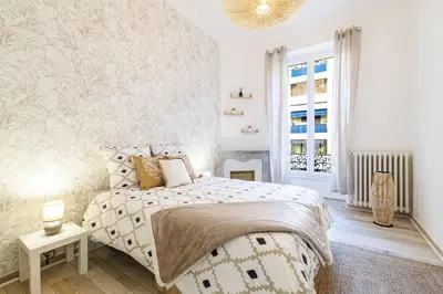 a white bedroom with a bed and a fireplace at 36 STALNGRAD - Appartement spacieux - Le Port - 6 pers in Nice