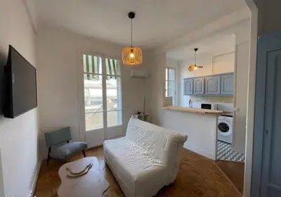 a living room with a white couch and a kitchen at Appartement Nice Centre Palais OPHELIA in Nice