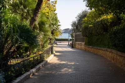 a road with a fence next to the water at Studio à 2min à pieds de la mer et du Casino in Beaulieu-sur-Mer