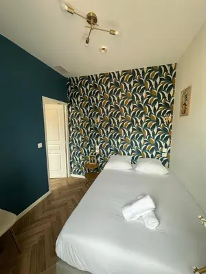 a bedroom with a large white bed with a patterned wall at Appartement 2 chb 1 SDB Nice - 32 in Nice