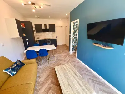 a living room with a couch and a table with blue chairs at MOON - 34 in Nice
