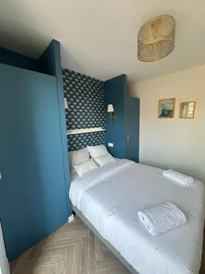 a bedroom with a large bed with a blue wall at MOON - 44 in Nice