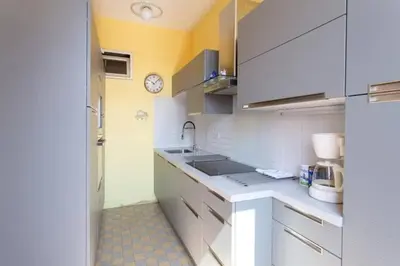 a kitchen with white cabinets and a clock on the wall at PANTHEON- App centre, 2 ch, 2 sdb , classé 4 étoiles in Nice