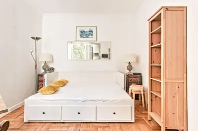 a bedroom with a white bed and a wooden cabinet at FLEUR- Cosy Studio, 200 Promenade des Anglais et Negresco, wifi, climatisation- calme in Nice