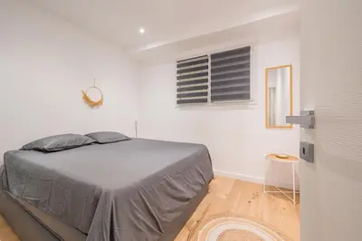 a white bedroom with a bed and a window at Le Duplex in Villefranche-sur-Mer