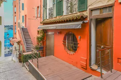 an orange building with a wooden walkway on a street at Le Duplex in Villefranche-sur-Mer