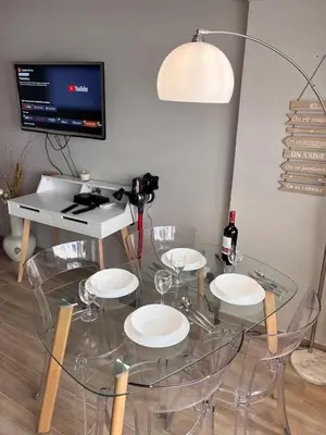 a room with a glass table with chairs and a tv at Studio at the heart of Carre D'or 2 mins Sea Wi-fi in Nice