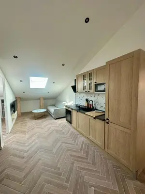 a large kitchen with wooden cabinets and a living room at GIOFFREDO SUITE in Nice