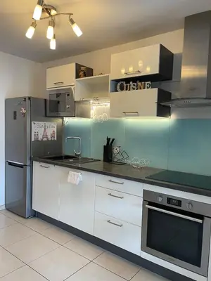 a kitchen with white cabinets and a stainless steel refrigerator at Nice modern flat in Nice