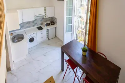 a kitchen with a table and a washing machine at GIOA- Studio avec balcon, place Garibaldi -Paillon in Nice