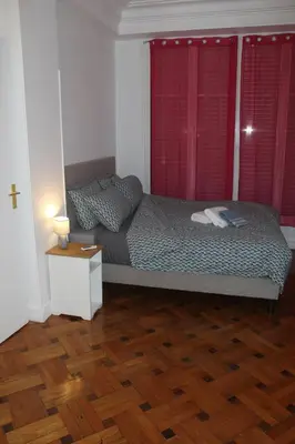a bedroom with a bed with red curtains and a wooden floor at LE REX Nice in Nice