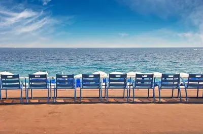 a row of blue chairs sitting on the beach at Iconic Central Flat in Nice