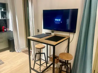 a desk with a tv on a wall with two stools at Suite ana in Nice