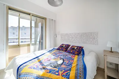 a bedroom with a bed with a comforter and a window at 2 pièces Calme Proche de la mer Parking en sous-sol in Cagnes-sur-Mer